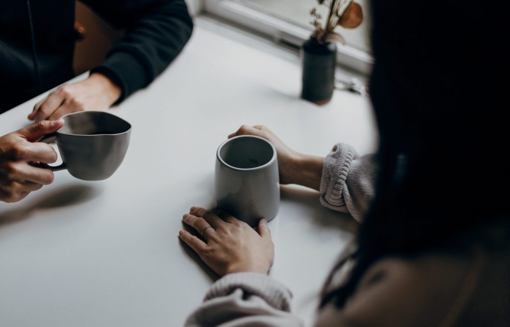 Cafe culture: People sitting at table with drinks in mugs