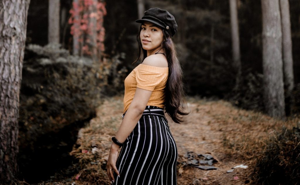 Best Fall Fashion: Woman in orange top and black-and-white striped pants in the woods